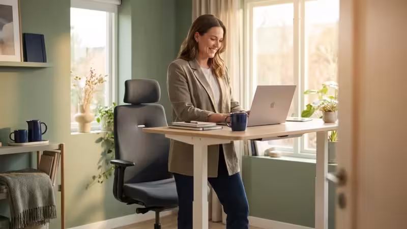 A professional woman working in a well-lit, modern home office with ergonomic furniture.
