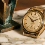 Vintage gold Patek Philippe Calatrava watch with leather strap displayed on a marble surface